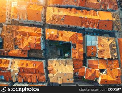Aerial view of houses with orange roofs at sunset in summer in Dubrovnik, Croatia. Top view of beautiful architecture in european old city. Historical centre, buildings, street in the evening. Travel