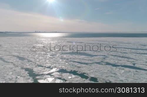 Aerial view of ice on the cold sea with view to the city and with sunlight