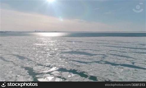 Aerial view of ice on the cold sea with view to the city and with sunlight