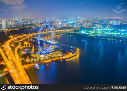 Aerial view of illuminated Singapore metropolis at night, embankment with ferris wheel ad city highway