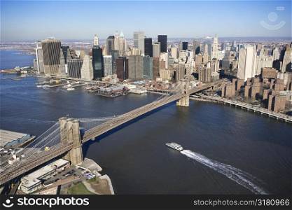 Aerial view of in New York City with Brooklyn Bridge and Manhattan skyline with ferry boat.