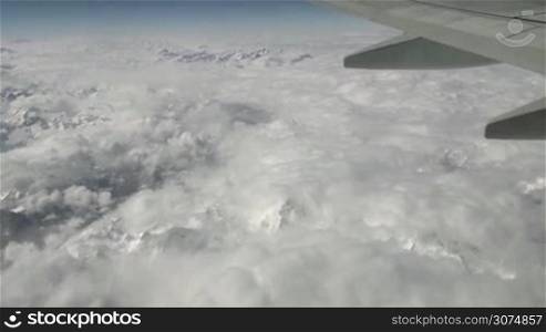 Aerial view of Italian and Swiss Alps. Mountain range covered with snow, clouds seen from sky on airplane, plane flying over mountains. Landscape, travel, aircraft flight above Italy and Switzerland