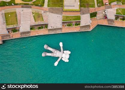 Aerial view of KAWS companion, giant sculpture floating on water. Figure in Victoria Harbour, Hong Kong. Republic of China