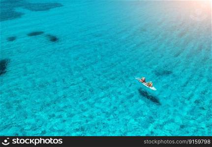 Aerial view of kayak with people in blue sea at summer sunny day. Man and woman on floating canoe in clear azure water. Sardinia island, Italy. Tropical landscape. Sup board. Active travel. Top view