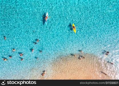 Aerial view of kayaks, swimming people in blue sea and sandy beach at summer sunny day. Sardinia, Italy. Top view from drone of canoes, shore, transparent water. Colorful tropical landscape. Travel