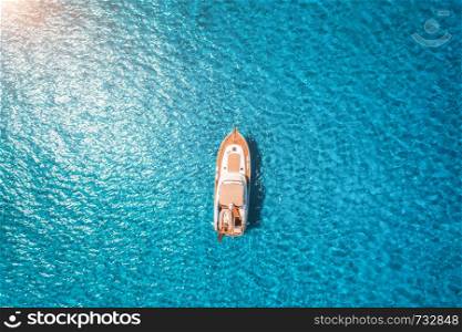 Aerial view of luxury yacht in transparent blue sea at sunset in summer in Mallorca, Spain. Colorful landscape with boat, bay, clear azure water. Top view from air. Travel. Seascape with motorboat