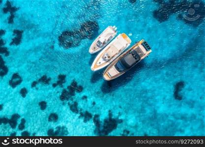 Aerial view of luxury yachts and boats on blue sea at summer sunny day. Travel in Sardinia, Italy. Drone view from above of speed boats, yachts, sea bay, rocky coast, transparent azure water. Seascape