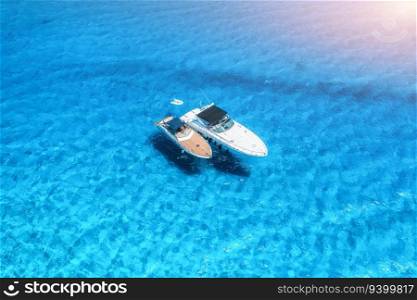 Aerial view of luxury yachts and boats on blue sea at sunrise in summer. Travel in Sardinia, Italy. Drone view from above of motorboats, yachts, sea lagoon, transparent azure water. Seascape. Top view