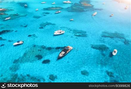 Aerial view of luxury yachts and boats on blue sea at sunrise in summer. Travel in Sardinia, Italy. Drone view from above of motorboats, yachts, sea lagoon, transparent azure water. Seascape. Top view