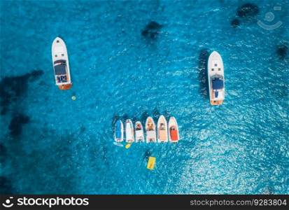 Aerial view of luxury yachts and boats on blue sea at sunset in summer. Travel in Sardinia, Italy. Drone view from above of speed boats, yachts, sea lagoon, transparent turquoise water. Seascape