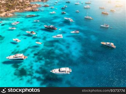Aerial view of luxury yachts and boats on blue sea at sunset in summer. Travel in Sardinia, Italy. Drone view from above of sailboats, yachts, sea bay, transparent azure water. Seascape. Top view