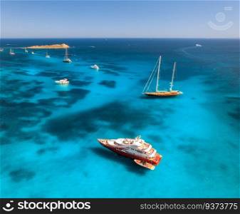 Aerial view of luxury yachts and boats on blue sea at sunset in summer. Travel in Sardinia, Italy. Drone view from above of sailboats, yachts, sea lagoon, transparent turquoise water. Seascape