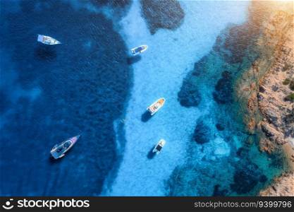 Aerial view of luxury yachts and boats on blue sea at sunset in summer. Travel in Sardinia, Italy. Drone view from above of speed boats, yachts, sea bay, rocky coast, transparent water. Seascape