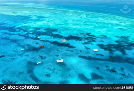 Aerial view of luxury yachts and fishing boats in clear blue sea at sunny day in summer. Top view from drone of boat. Travel in Zanzibar, Africa. Colorful landscape with motorboat in transparent water