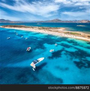 Aerial view of luxury yachts on blue sea and sandy beach at sunny day in summer. Sardinia, Italy. View from above of boats, yachts, sea bay, sea spit, clear water, sky. Top view. Tropical seascape