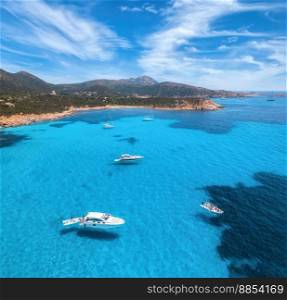 Aerial view of luxury yachts on blue sea at sunny day in summer. Sardinia, Italy. Aerial view of speed boats, yachts, sea lagoon, shore, transparent water, sky. Top view from drone. Tropical seascape 