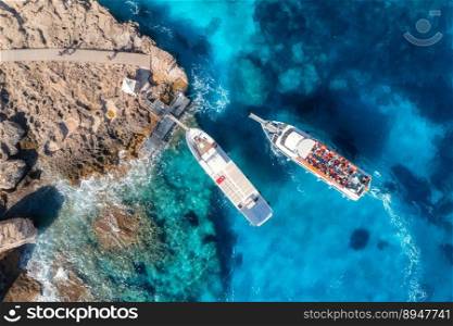 Aerial view of luxury yachts on blue sea at sunny day in summer. Sardinia, Italy. Aerial view of boats, rocky beach, sea lagoon, shore, transparent water. Top view from drone. Tropical seascape	