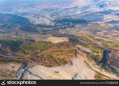 Aerial view of machine excavator trucks dig coal mining or ore with black grunge ground in quarry with mountain hills. Nature landscape background in factory industry. Environment resources