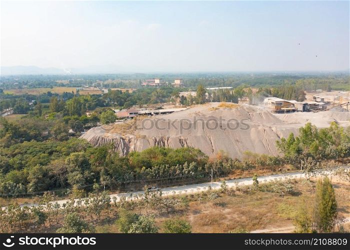 Aerial view of machine excavator trucks dig coal mining or ore with black grunge stone on ground in quarry with mountain hills. Nature landscape background in factory industry. Environment resources