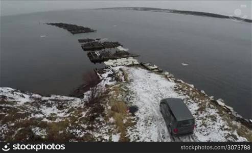 Aerial view of minivan standing by waterside with unfinished bridge with following view to the Rabocheostrovsk, township on the White Sea coast near Solovki