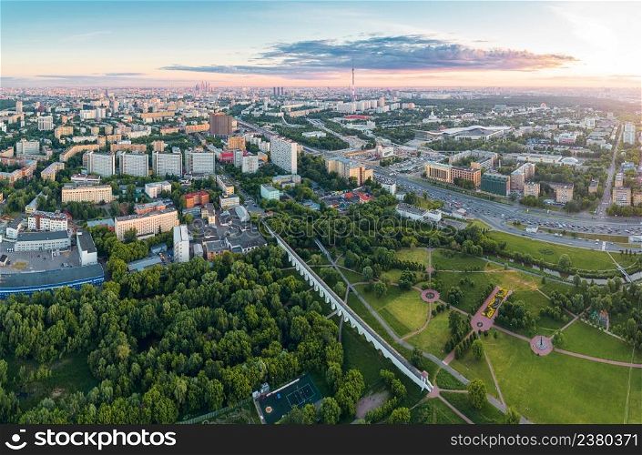 Aerial view of Moscow over the Rostokino Aqueduct (Millionny Bridge) and the park around it at summer sunset. There are distant VDNKh park, Ostankino tower and Moscow City business center skyscrapers