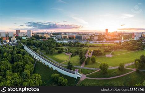 Aerial view of Moscow over the Rostokino Aqueduct (Millionny Bridge) and the park around it at summer sunset. There are distant VDNKh park and Ostankino tower