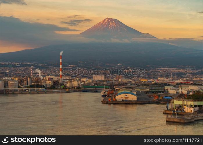 Aerial view of Mountain Fuji near industrial area, factory, Japanese port and harbour in Shizuoka City at sunset, Japan. Natural landscape background.