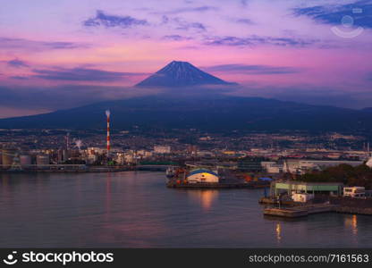 Aerial view of Mountain Fuji near industrial area, factory, Japanese port and harbour in Shizuoka City at sunset, Japan. Natural landscape background.