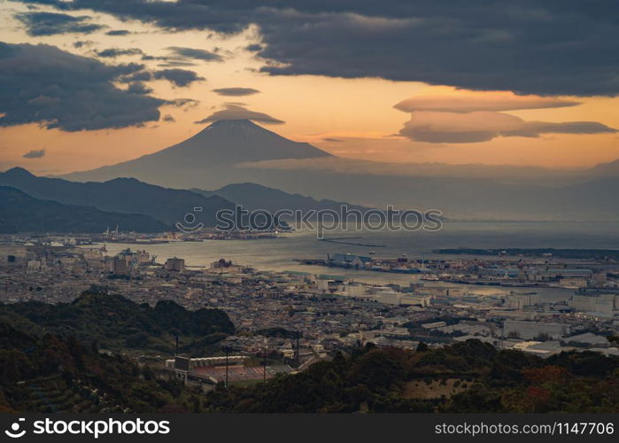 Aerial view of Mountain Fuji with hat cloud near industrial area, Japanese port and harbour in Shizuoka City at sunset, Japan. Natural landscape background.