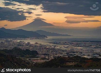 Aerial view of Mountain Fuji with hat cloud near industrial area, Japanese port and harbour in Shizuoka City at sunset, Japan. Natural landscape background.