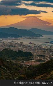 Aerial view of Mountain Fuji with hat cloud near industrial area, Japanese port and harbour in Shizuoka City at sunset, Japan. Natural landscape background.