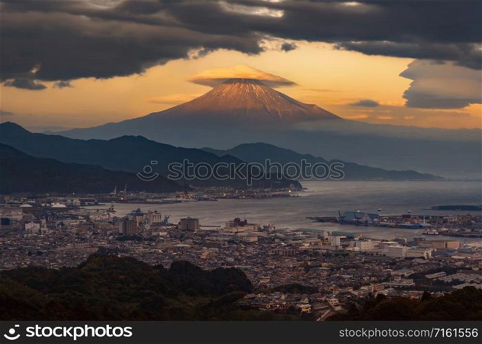 Aerial view of Mountain Fuji with hat cloud near industrial area, Japanese port and harbour in Shizuoka City at sunset, Japan. Natural landscape background.