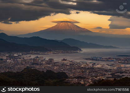 Aerial view of Mountain Fuji with hat cloud near industrial area, Japanese port and harbour in Shizuoka City at sunset, Japan. Natural landscape background.