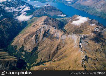 Aerial view of mountain ranges and lake landscape. Panoramic shot from airplane flying above mountains near Lake Wakapitu in Queenstown, New Zealand.