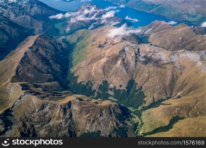 Aerial view of mountain ranges and lake landscape. Panoramic shot from airplane flying above mountains near Lake Wakapitu in Queenstown, New Zealand.