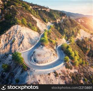 Aerial view of mountain road, green forest at sunset in summer in Greece. Top view from drone of road in woods. Beautiful landscape with roadway in hills, pine trees, white rocks in spring. Travel