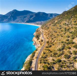 Aerial view of mountain road near blue sea, sandy beach at sunset in summer. Oludeniz, Turkey. Top view of road, trees, clear water, mountain. Beautiful landscape with highway, rocks and sea coast