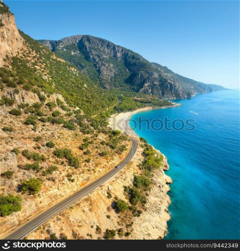 Aerial view of mountain road near blue sea, sandy beach at sunset in summer. Oludeniz, Turkey. Top view of road, trees, clear water, mountain. Beautiful landscape with highway, rocks and sea coast	