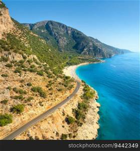 Aerial view of mountain road near blue sea, sandy beach at sunset in summer. Oludeniz, Turkey. Top view of road, trees, clear water, mountain. Beautiful landscape with highway, rocks and sea coast	