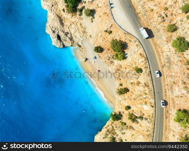 Aerial view of mountain road near blue sea, sandy beach at sunset in summer. Oludeniz, Turkey. Top view of road, trees, clear water, mountain. Beautiful landscape with highway, rocks and sea coast 