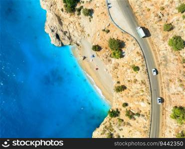 Aerial view of mountain road near blue sea, sandy beach at sunset in summer. Oludeniz, Turkey. Top view of road, trees, clear water, mountain. Beautiful landscape with highway, rocks and sea coast 
