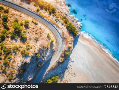 Aerial view of mountain road near blue sea with sandy beach at sunset in summer. Oludeniz, Turkey. Top view of road, trees, azure water, mountain. Beautiful landscape with highway, rocks, sea coast
