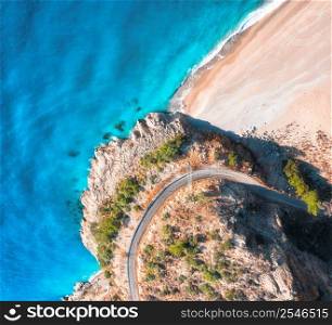 Aerial view of mountain road near blue sea with sandy beach at sunset in summer. Oludeniz, Turkey. Top view of road, trees, azure water, mountain. Beautiful landscape with highway, rocks, sea coast