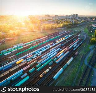 Aerial view of multicolored freight trains. Cargo wagons on railway station. Wagons with goods on railroad. Heavy industry. Industrial landscape with train, railway platfform at sunset. Top view.Depot. Aerial view of colorful freight trains on railroad