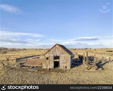 aerial view of northern Colorado landscape in fall or winter scenery - abandoned wooden barn and cattle fence