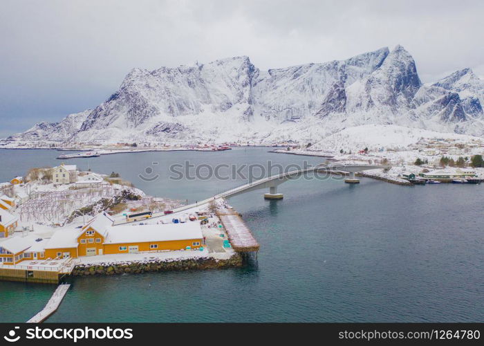 Aerial view of Norwegian fishing village in Reine City, Lofoten islands, Nordland, Norway, Europe. White snowy mountain hills, nature landscape background in winter season. Famous tourist attraction