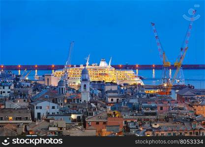 Aerial view of old town and port with cranes and ship at night, Genoa, Italy.