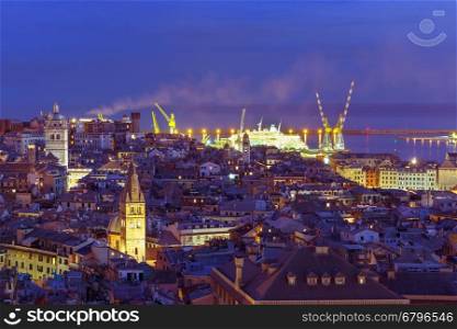 Aerial view of old town and port with cranes at night, Genoa, Italy.