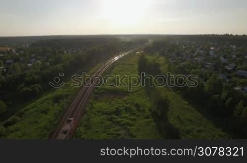 Aerial view of passenger train running through the village in Russia