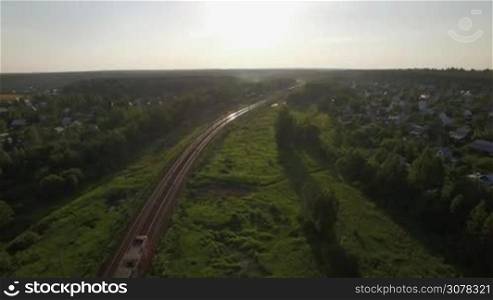 Aerial view of passenger train running through the village in Russia